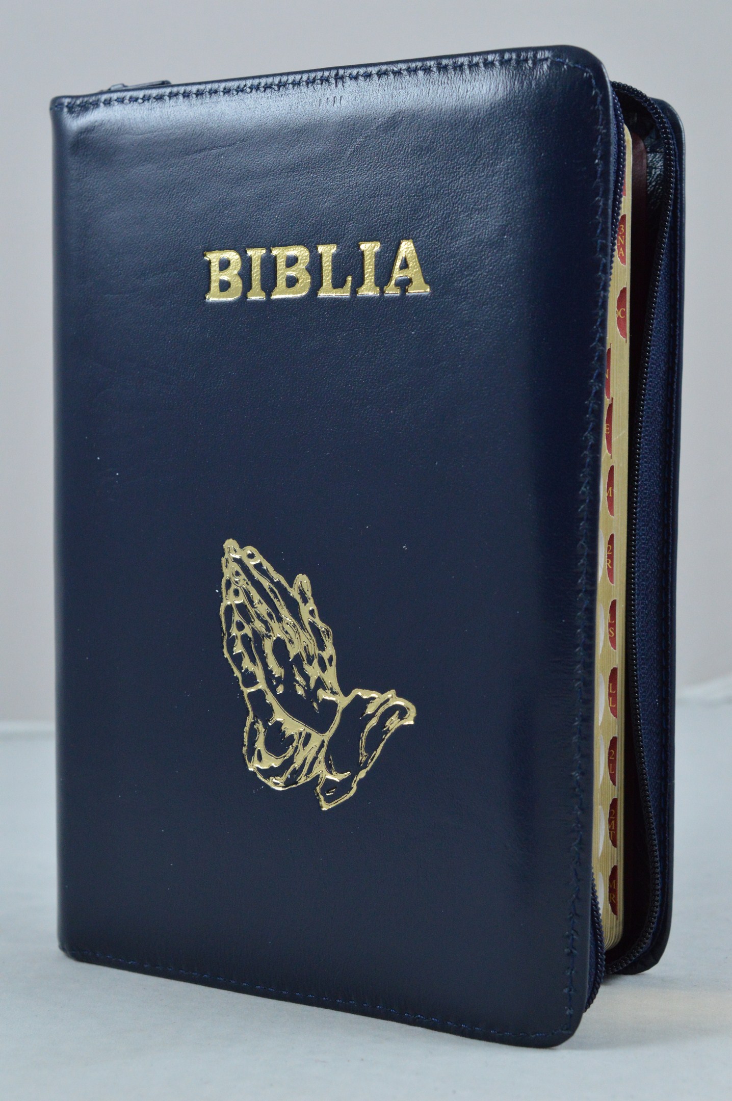 Biblie din piele, marime medie, culoare albastru inchis  lucios simbol maini in rugaciune, fermoar, index, margini aurii, cuv. lui Isus cu rosu [SB 057 PFI]
