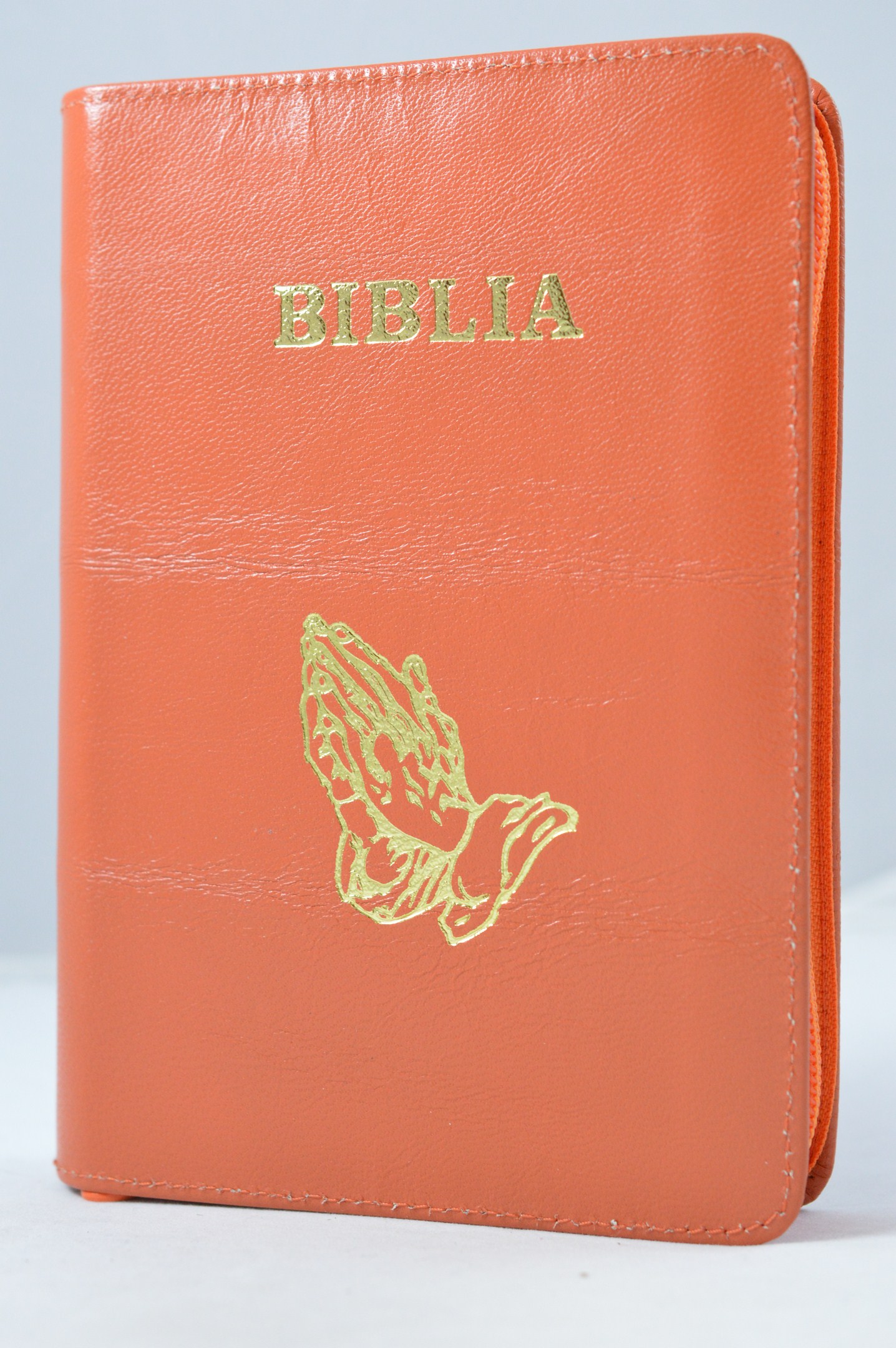 Biblia din piele, marime medie, culoare portocaliu, fermoar, simbol maini in rugaciune, margini albe,cuv. lui Isus cu rosu [053]